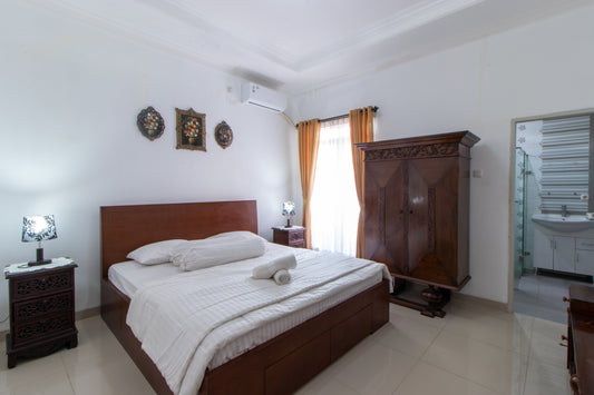 kamar tidur dengan kasur king size yang mengunakan dipan kayu dengan hiasan nakas kecil yang terdapat lampu diatasnya, lemari kayu jati yang tersedia bisa kamu gunakan untuk menyimpan barang bawaan yang kamu bawa saat menginap di villa bandung