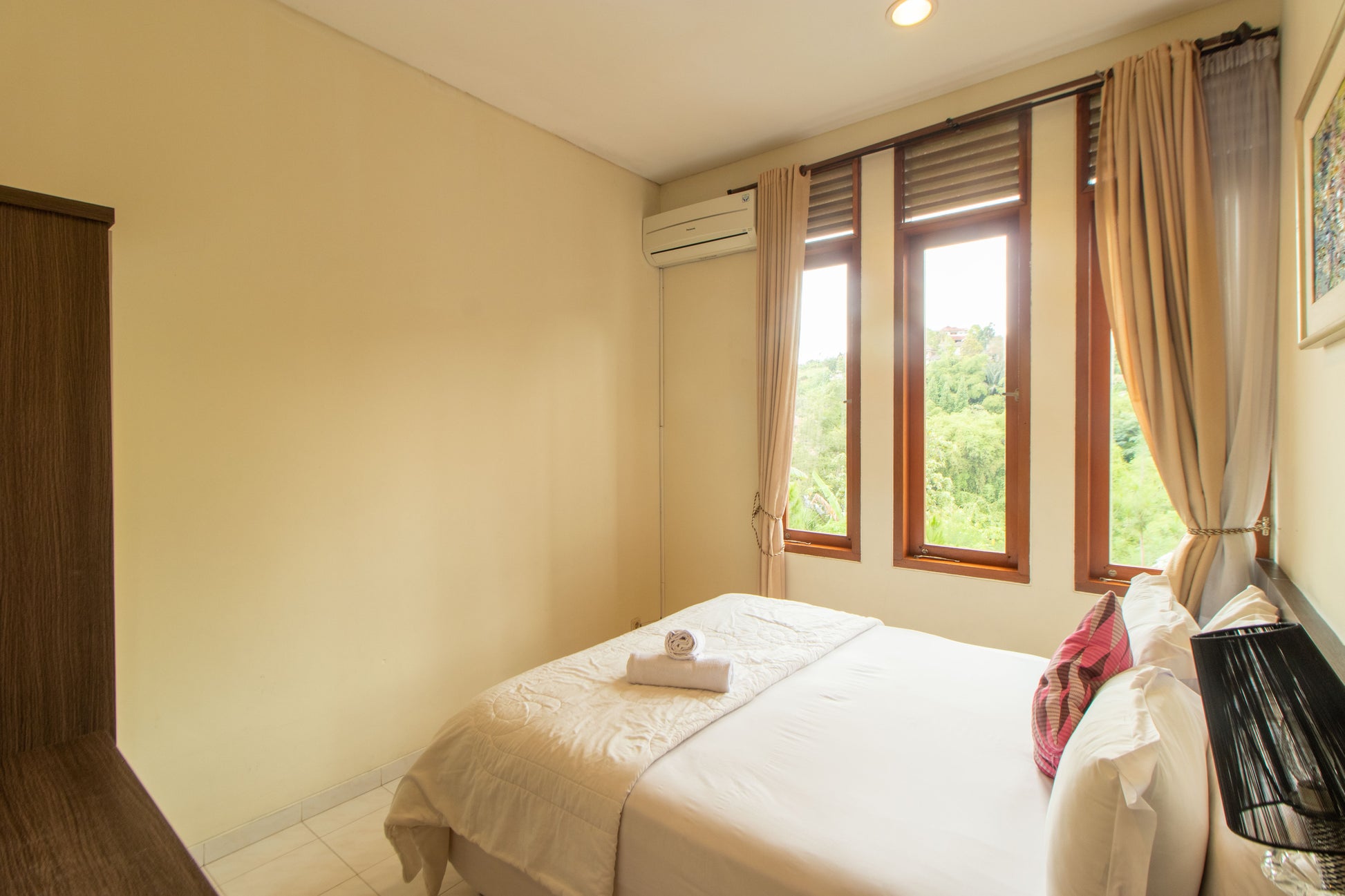 Tempat tidur yang cukup besar dengan 4 buah bantal, selimut dan juga handuk salah satu fasilitas villa yang bisa kamu nikmati, meskipun udara di bandung sudah dingin tapi kamar ini sudah dilengkapi ac.