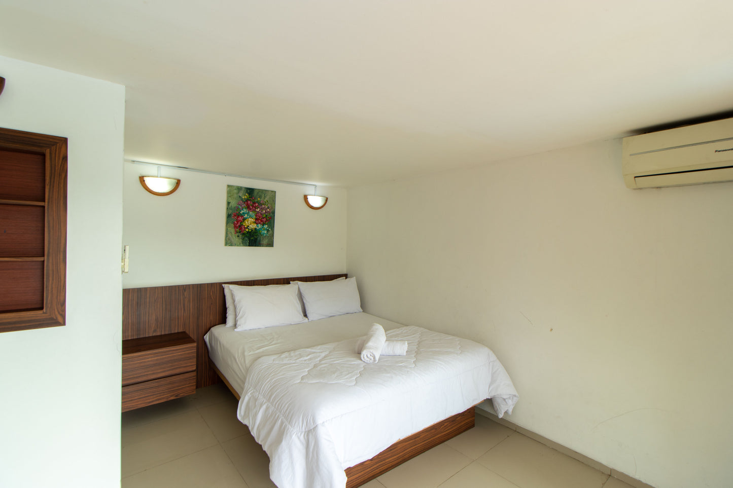 Ruangan yang cukup luas untuk kamar tidur dengan kasur berukuran besar, laci kecil disamping kasur dan hiasan lampu tidur yang menempel di dinding bersama lukisan bunga menambah suasana kehangatan saat menginap di Villa. meski cuaca di bandung sudah dingin tetapi semua kamar tidur sudah dilengkapi AC.