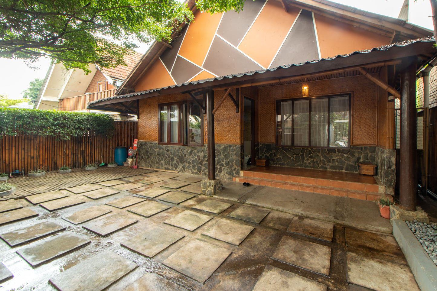 Villa nuansa asri khas Bandung dengan pondasi batu dan dinding yang terbuat dari anyaman bambu dihiasi dengan lampu gantung berwarna kuning dan dua tiang menjulang di depan rumah untuk sebagai penunjang, dikelilingi pagar bambu dan sedikit taman di teras, lantai carport yang terbuat dari paving block dan bisa menampung 2 unit mobil.