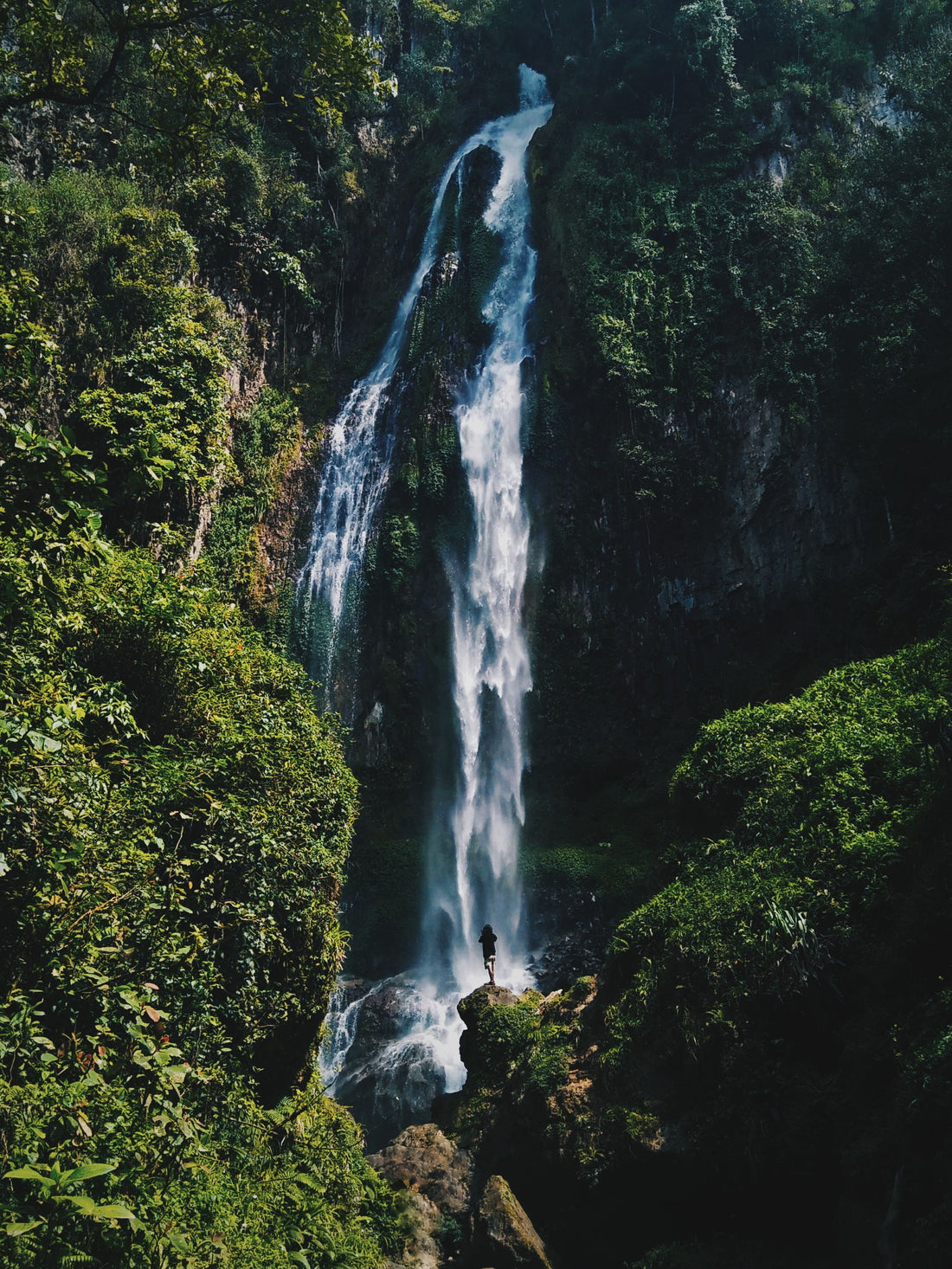 Air terjun tersembunyi dikelilingi hutan tropis, mewakili curug-curug di sekitar Bandung