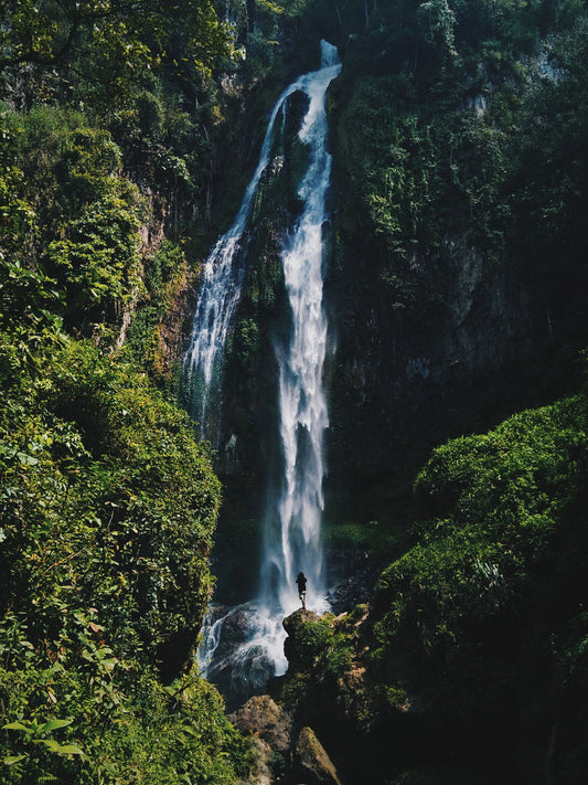 Air terjun tersembunyi dikelilingi hutan tropis, mewakili curug-curug di sekitar Bandung