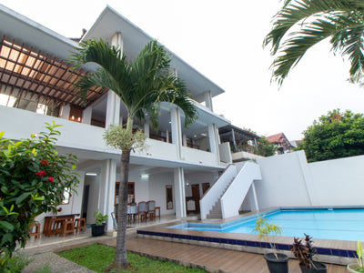 Villa dua lantai dengan kolam renang pribadi yang bersih, dikelilingi pepohonan hijau dan pohon palem. Vila ini memiliki eksterior putih dengan balkon dan ruang makan beratap yang langsung menghadap pemandangan bukit bukit yang ada di dago bandung 