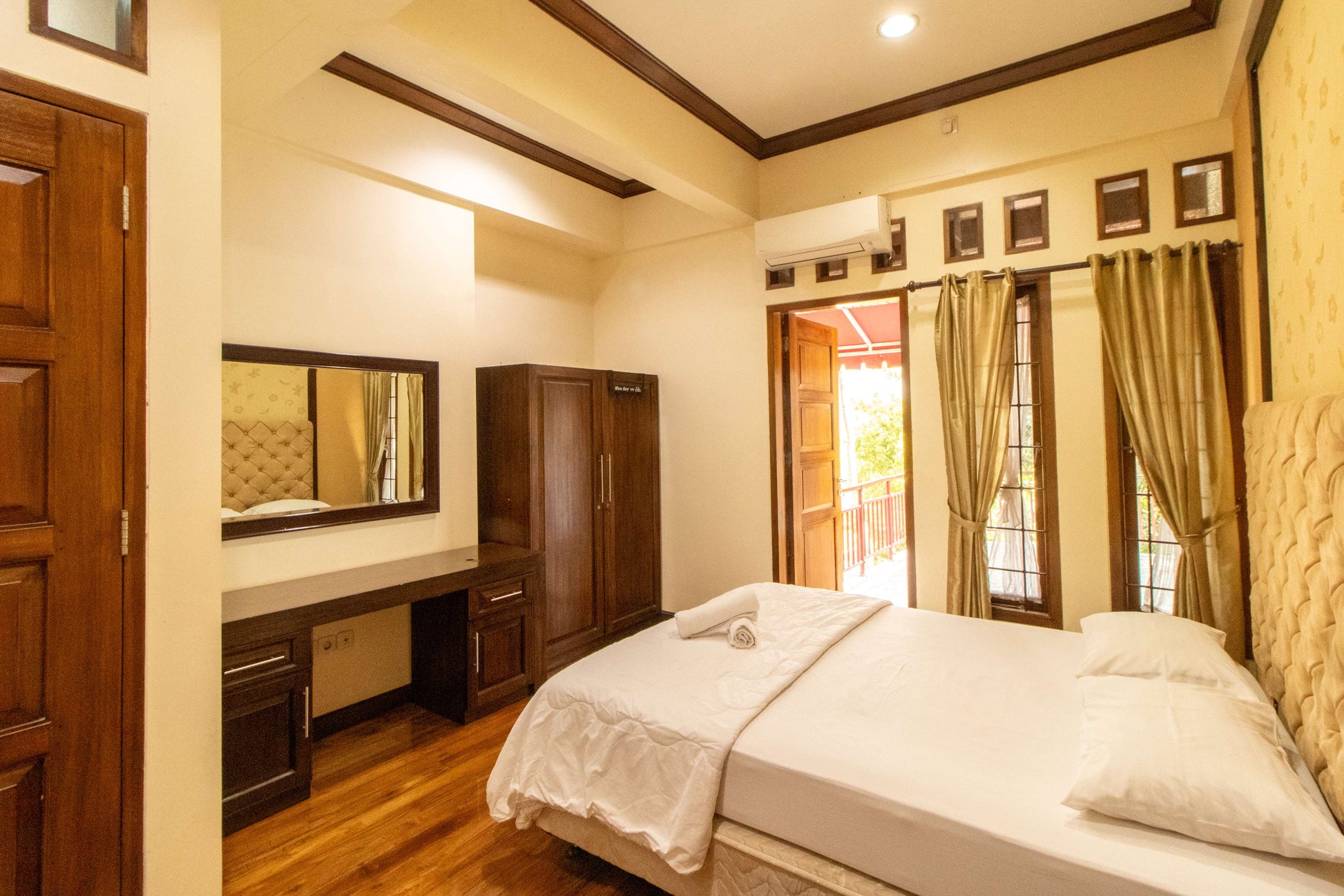 Kamar tidur Villa Dago35 dengan lemari kayu, meja rias, dan akses balkon
