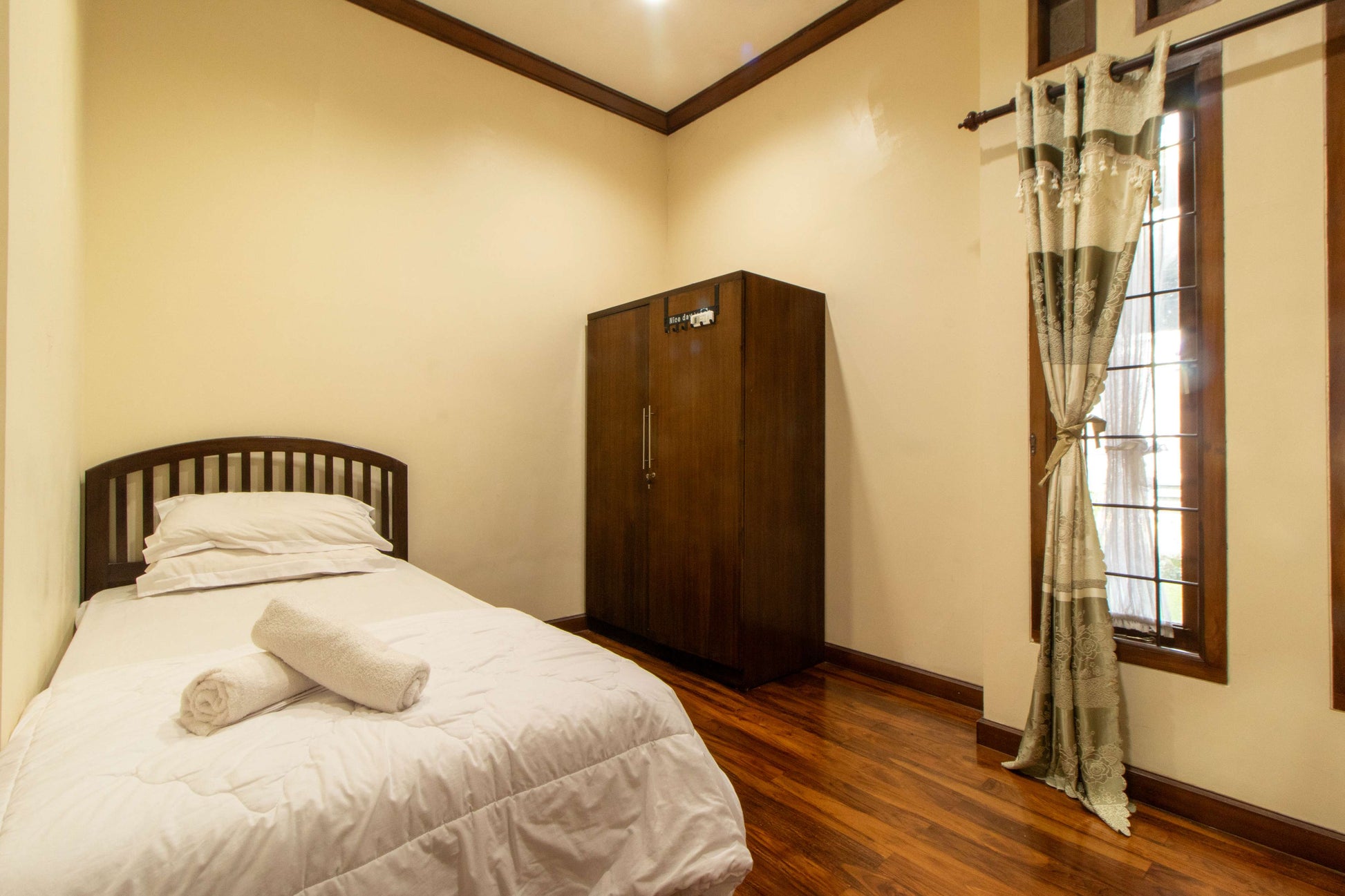 Kamar tidur single di Villa Dago35 dengan lemari kayu dan jendela bertirai