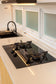 Siapkan hidangan favorit keluarga di dapur villa yang dirancang dengan konsep modern minimalis. Keberadaan kompor gas berwarna hitam memberikan sentuhan mewah sekaligus tangguh, sangat kontras dan cantik di dalam ruangan. Area memasak ini juga dilengkapi dengan wastafel cuci piring (sink) yang dalam dan bersih, memastikan aktivitas memasak kamu tetap praktis, higienis, dan menyenangkan.